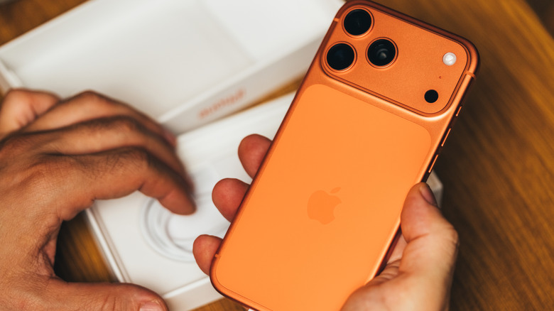 Un iPhone 17 orange en cours de déballage.