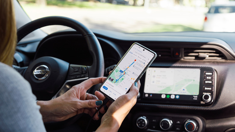 Une conductrice compare Google Maps sur son téléphone avec Google Maps sur l'écran de sa voiture