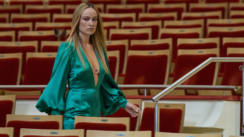 Olivia Wilde dans le rôle de Carol Spedding portant une robe verte et traversant un théâtre vide dans Behemoth !