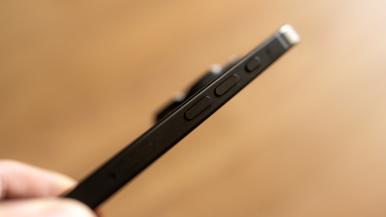 Une personne montrant le côté des boutons d'action et de volume d'un iPhone