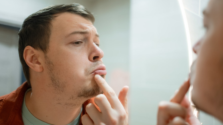 Homme examinant ses lèvres dans un miroir