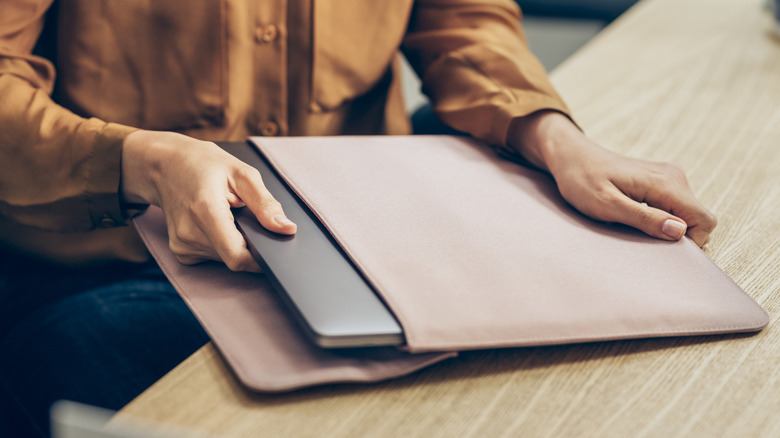 Une personne avec un ordinateur portable et une pochette pour ordinateur portable
