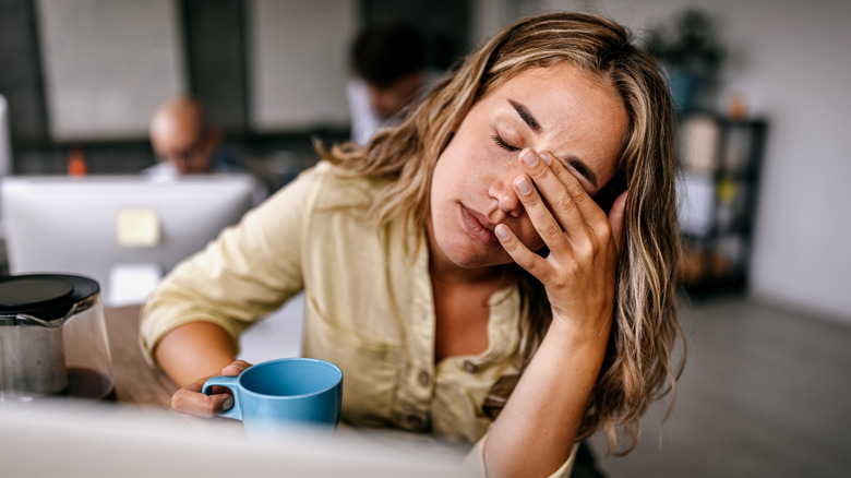 Jeune femme semblant épuisée tout en tenant une tasse de café