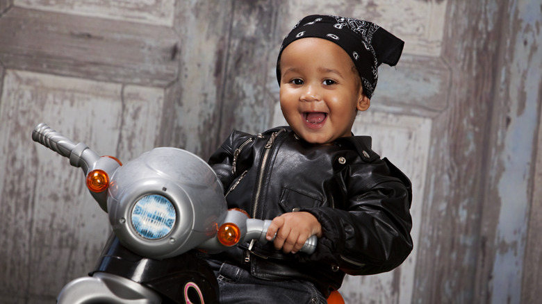 Bébé dans une veste en cuir sur une moto jouet