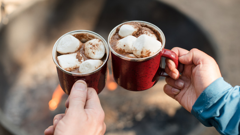 Tasses de chocolat chaud avec des guimauves au-dessus d'un feu de camp