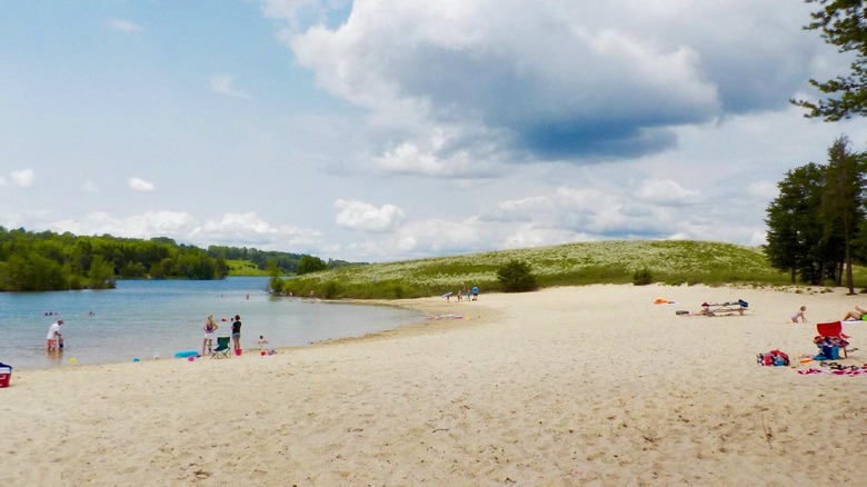 les gens se tiennent debout et s'allongent sur la large plage de sable du lac Wazee