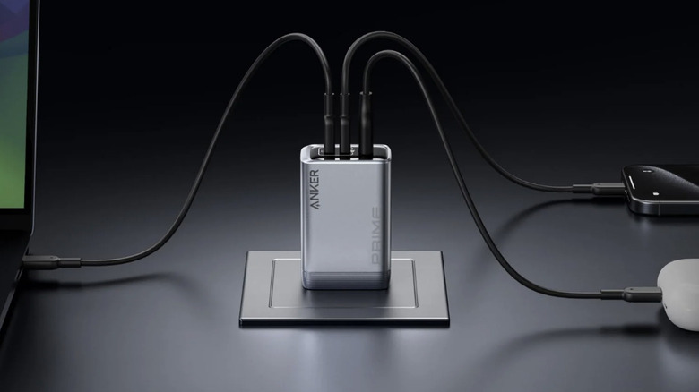 Gros plan d'un chargeur mural Anker branché sur trois appareils, dont un ordinateur portable et un smartphone