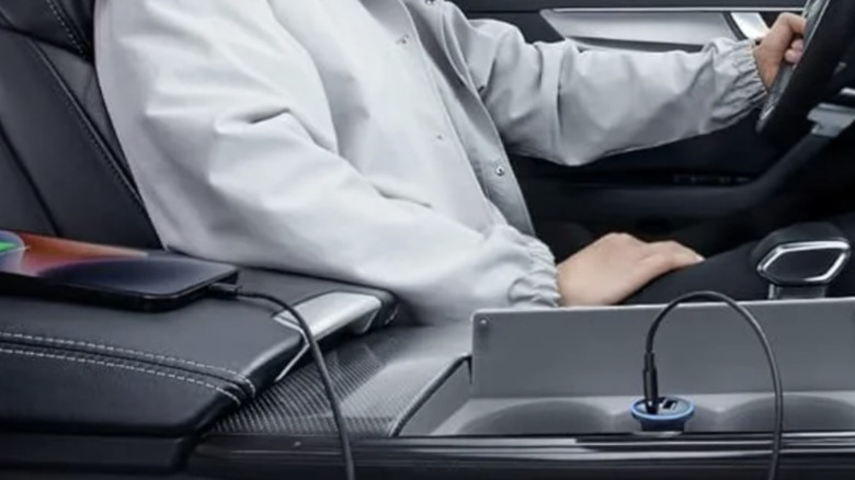 Gros plan d'une personne utilisant un chargeur de voiture Anker à l'intérieur de son véhicule pour charger un téléphone intelligent