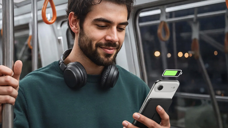 Un homme dans un métro tenant son smartphone avec une banque d'alimentation Anker connectée sans fil