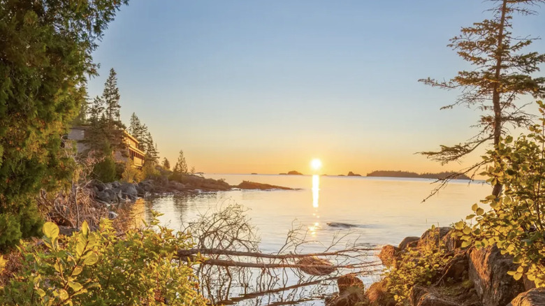 Des arbres jaunes encadrent une crique sur les rives du parc national de l'Isle Royale, surplombant un coucher de soleil sur le lac Supérieur.
