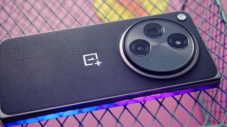 Gros plan du smartphone OnePlus 15 posé sur une surface filaire.