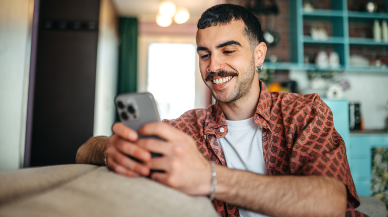 Une personne souriant en utilisant son smartphone.