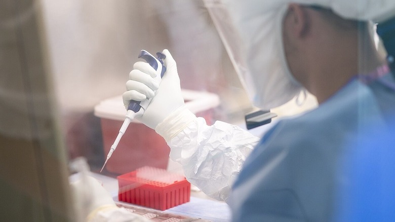 Un scientifique du centre de recherche chimique de Fort Detrick en combinaison de matières dangereuses avec pipette à la main