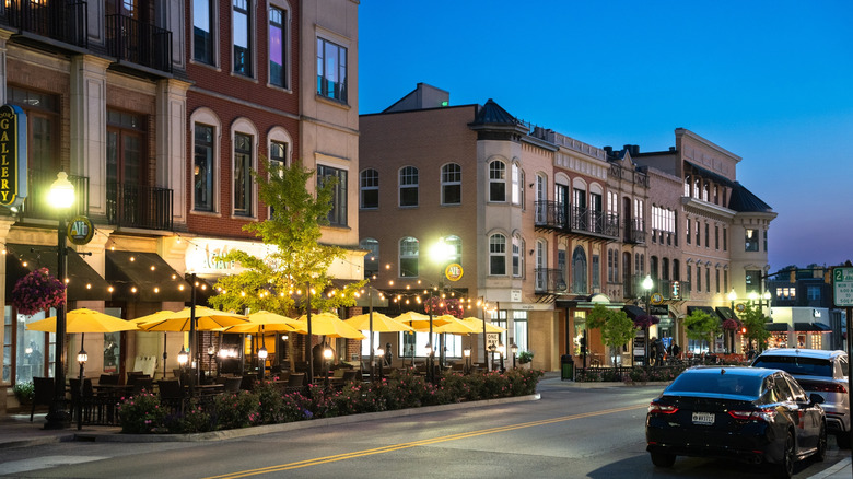 Vue en soirée sur une rue du centre-ville avec un café-terrasse et de charmants bâtiments à Carmel, Indiana