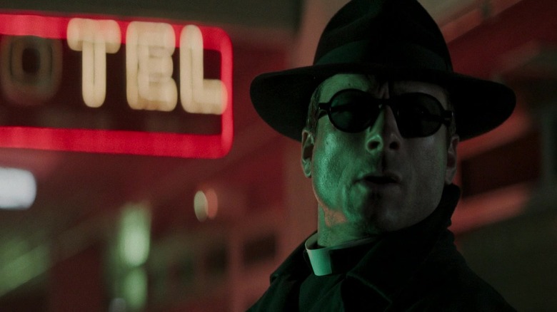 Ben Richards de Glen Powell regarde à sa gauche tout en portant un chapeau et des lunettes dans The Running Man