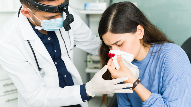 Médecin de sexe masculin aidant une patiente souffrant d'un saignement de nez