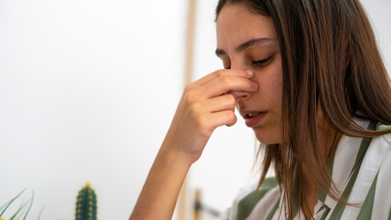 Femme avec la tête en position neutre, se pinçant le nez