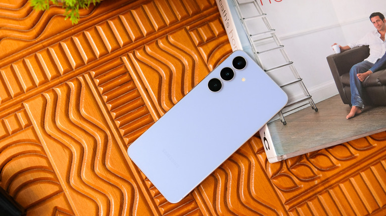 Un téléphone Samsung bleu à côté d’un livre.