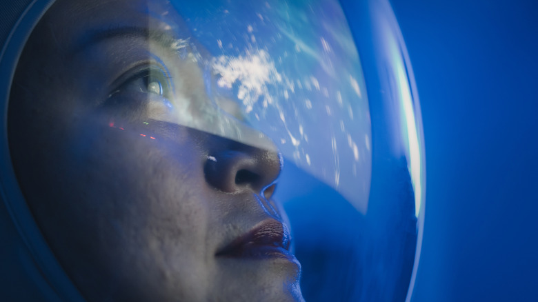 Une astronaute regardant la Terre depuis l'espace à travers son casque de combinaison spatiale