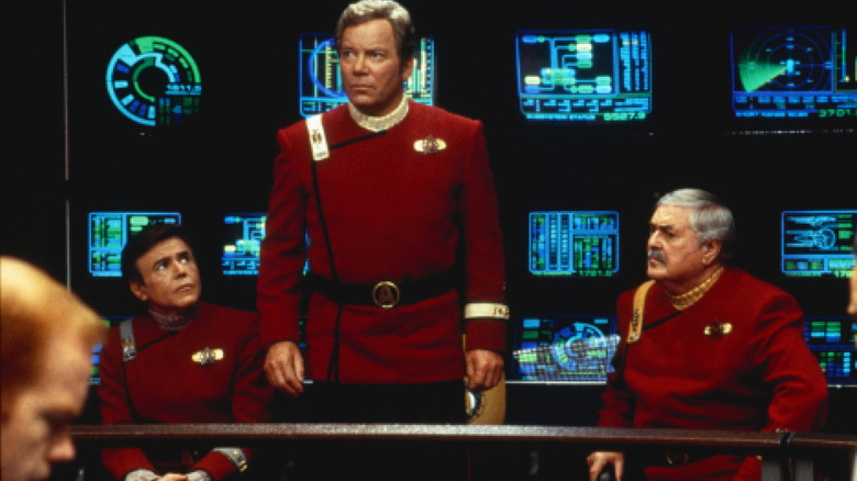 Walter Koenig dans le rôle de Pavel Chekov et James Doohan dans le rôle de Montgomery Scott assis entre William Shatner dans le rôle de James Kirk sur le pont d'un vaisseau spatial dans Star Trek : Generations