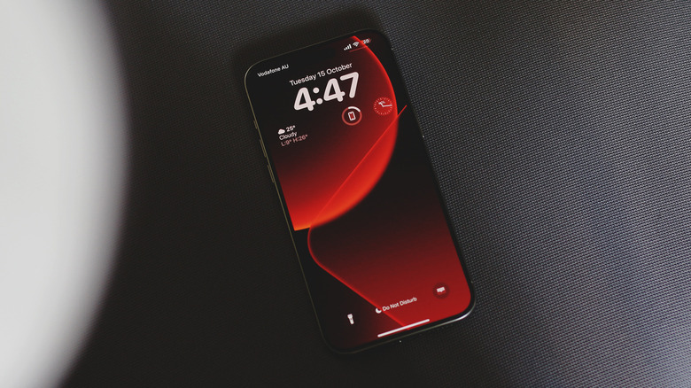 IPhone sur une surface texturée grise avec un papier peint rouge et noir.