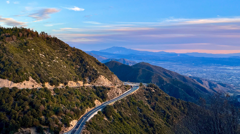 Une route serpentant à travers les montagnes de San Bernardino et surplombant une ville au crépuscule au loin