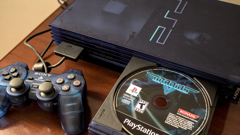 Une PS2 avec une manette bleue et une copie de Gradius.