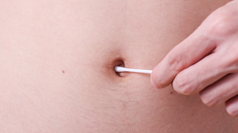 Personne utilisant un coton-tige pour nettoyer le nombril