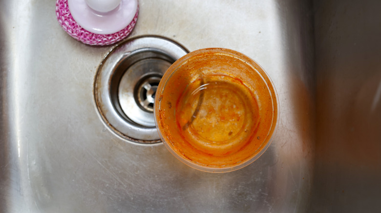 Vieux récipient alimentaire en plastique taché dans un évier