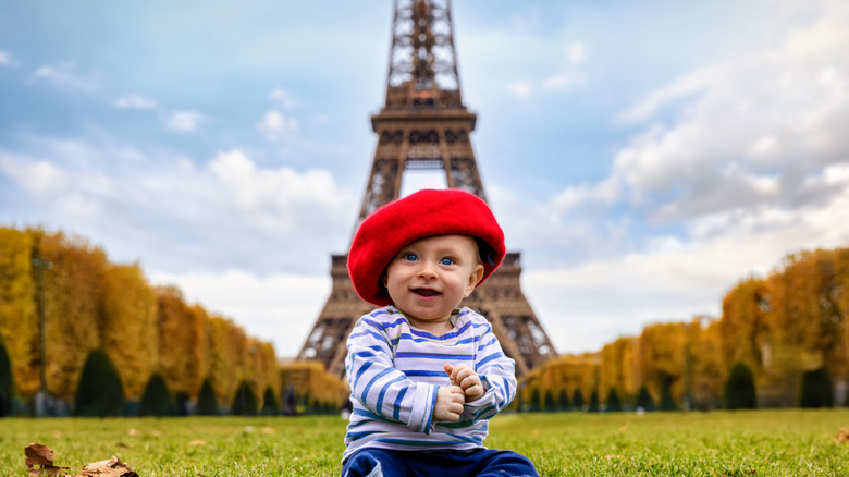 Un bébé portant un chapeau français devant la Tour Eiffel à Paris
