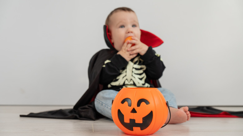 Un bébé en costume de vampire et décor de citrouille.
