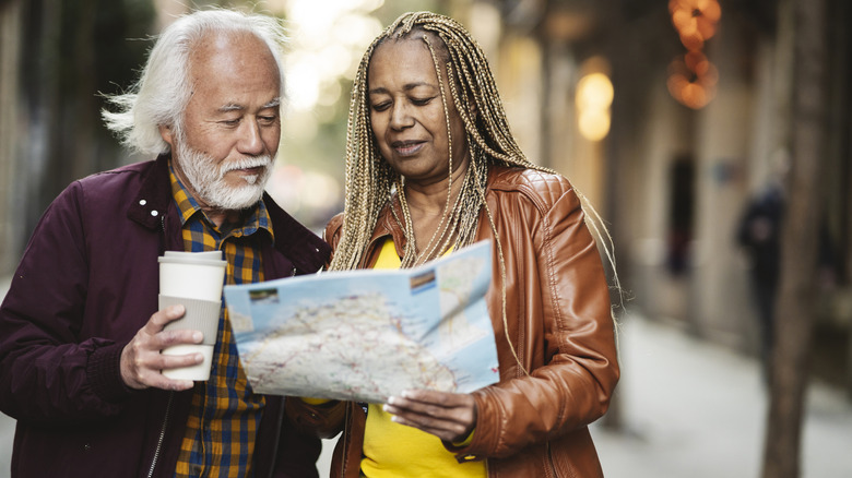 couple de personnes âgées lisant une carte