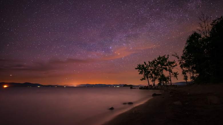 Une vue sur le Grand Lac Sacandaga la nuit, avec un ciel étoilé rose