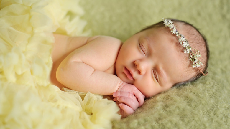 Un bébé qui dort avec un bandeau fleuri