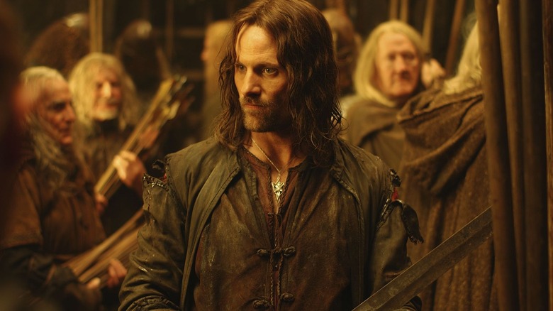 Viggo Mortensen dans le rôle d'Aragron tenant son épée pendant que les gens s'arment dans Le Seigneur des Anneaux : Les Deux Tours