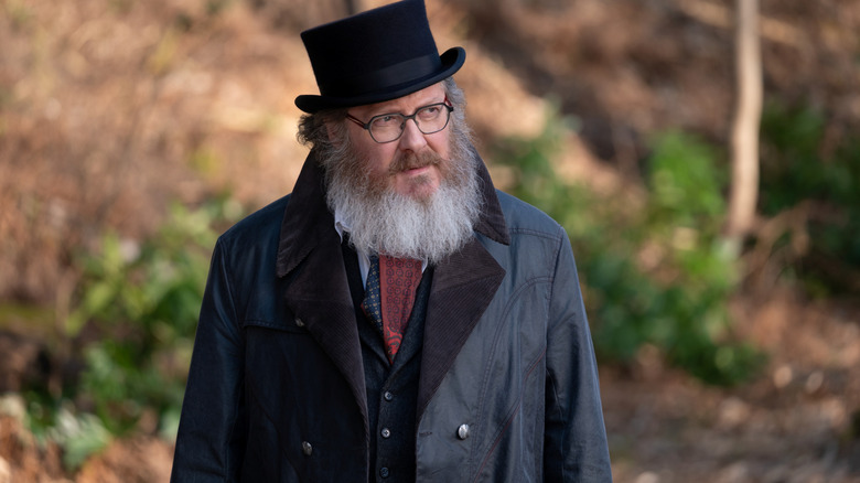 James Spader dans le rôle d'Ultron dans son avatar humain portant un haut-de-forme dans une zone boisée dans VisionQuest