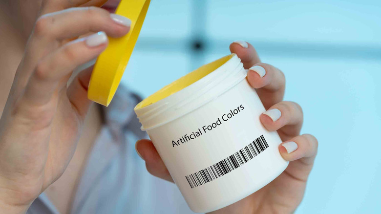 Personne ouvrant un pot de colorant alimentaire artificiel