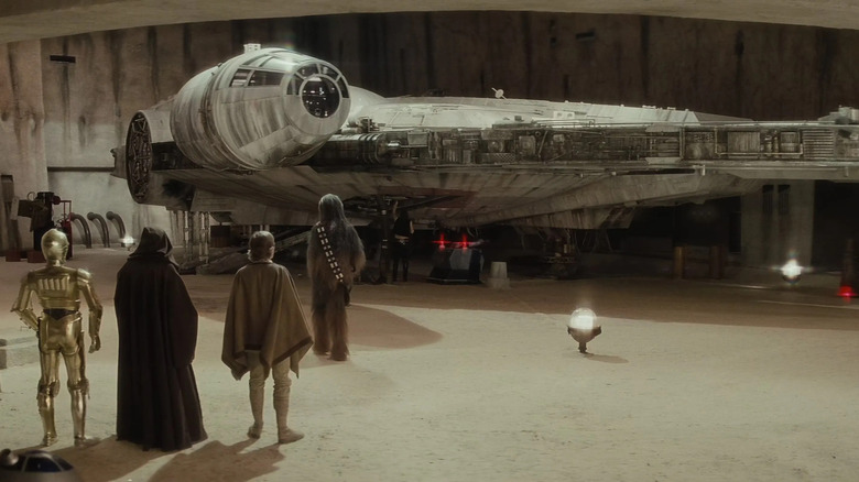 C-3PO, Obi-Wan Kenobi, Luke Skywalker et Chewbacca regardant le Faucon Millenium dans Star Wars : Épisode IV – Un nouvel espoir